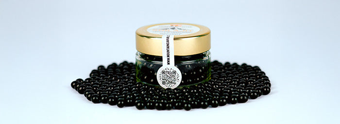 Jar of black caviar with a gold lid on a light gray background